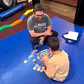 Alex K, pediatric occupational therapist at All Bright Therapies, playing a therapy game with a child